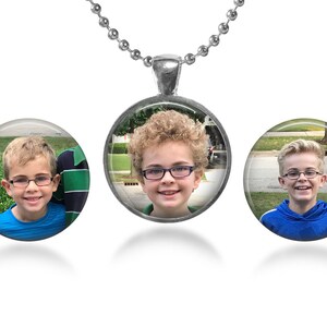 Puede incluir: Tres collares colgantes de plata con dijes redondos de vidrio que muestran fotos de niños pequeños con gafas. Cada dije tiene un borde plateado.