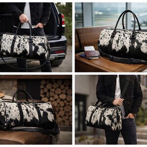 May include: A duffel bag featuring a black and white cowhide pattern with black leather handles, a detachable shoulder strap, and a top zipper closure. The bag has a cylindrical shape with reinforced black leather trim and metal hardware.