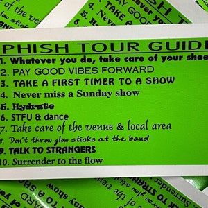 May include: Green and white sticker with the text "PHISH TOUR GUIDE" and a list of 10 tips for attending a Phish concert. The tips include "Take care of your shoes", "Pay good vibes forward", "Take a first timer to a show", "Never miss a Sunday show", "Hydrate", "STFU & dance", "Take care of the venue & local area", "Don't throw glow sticks at the band", "Talk to strangers", and "Surrender to the flow".