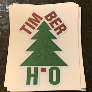 May include: A green Christmas tree with the words "Timber" and "H2O" in brown letters on a white background.