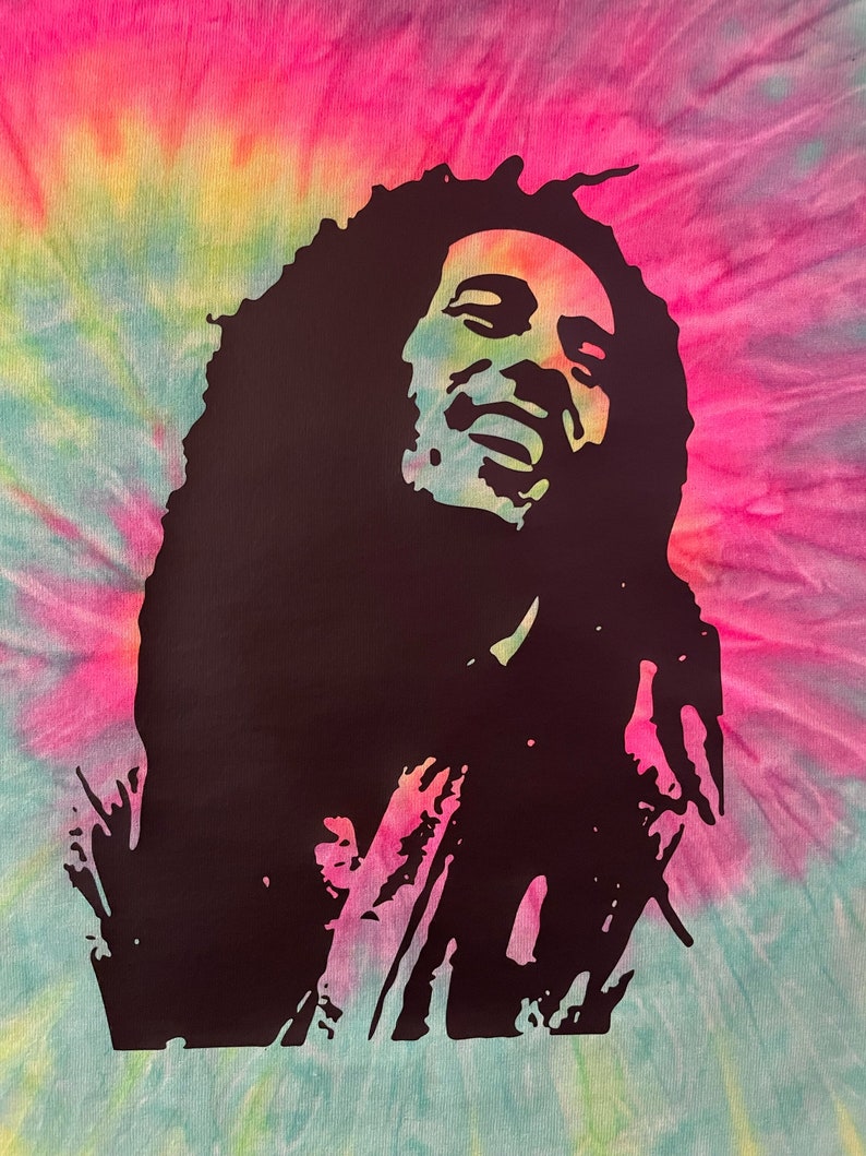 May include: A black silhouette of Bob Marley with dreadlocks, singing with his eyes closed and hands raised. The background is a tie-dye pattern in shades of pink, yellow, and blue.