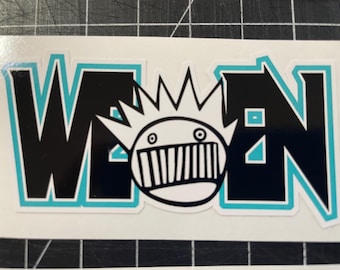 May include: A black and white sticker with the word "WEEN" in a bold, stylized font. A cartoon face with a spiky crown and a toothy grin is centered between the letters.