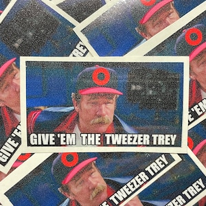 May include: A sticker with a photo of a man wearing a red and white baseball cap with a red circle on it. The man is looking to the right and has a mustache. The text on the sticker says "Give 'em the Tweezer Trey".