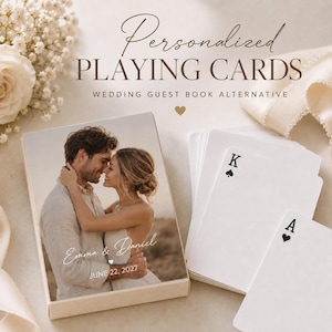 Könnte beinhalten: Ein personalisiertes Kartenspiel in einer Schachtel mit einem Foto eines Paares und dem Text Emma & Daniel sowie JUNE 22, 2027. Die Schachtel ist mit Personalized PLAYING CARDS WEDDING GUEST BOOK ALTERNATIVE beschriftet. Zwei Karten zeigen König und Ass.