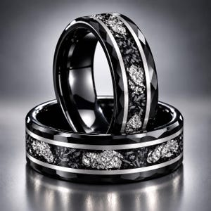 Op de afbeelding: Twee zwarte ringen met een gefacetteerde buitenrand en een centrale inleg met een mix van donkergrijs en glinsterend zilverkleurig vergruisd materiaal, omrand door twee dunne, gepolijste zilverkleurige metalen banden.