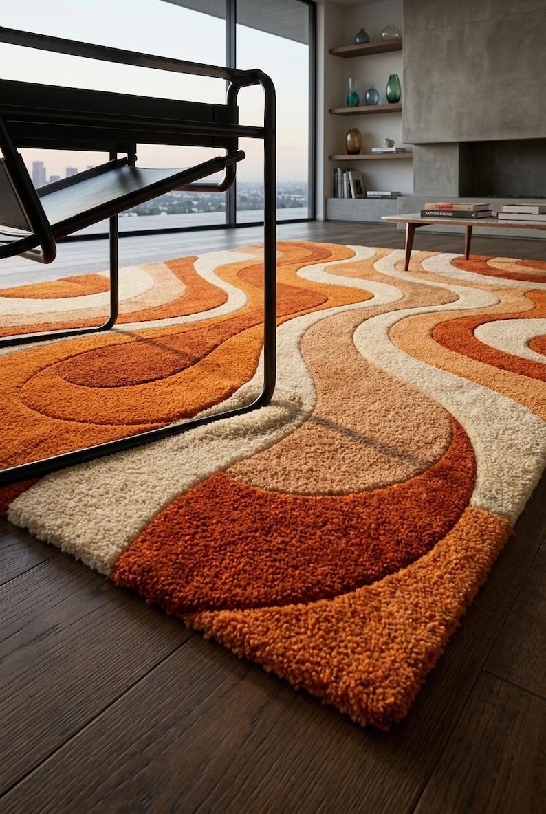 May include: A retro-style area rug with a wavy pattern in shades of orange, beige, and cream. The rug has a thick, textured pile and is placed on a dark wood floor. A black chair is partially visible in the foreground.