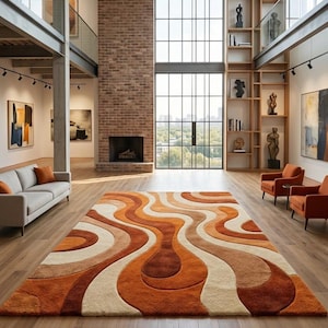 May include: A large, retro-style area rug with a wavy pattern in shades of orange, brown, and cream. The rug is the focal point of a spacious room with hardwood floors, a brick fireplace, and large windows. The room also features a sofa and armchairs.