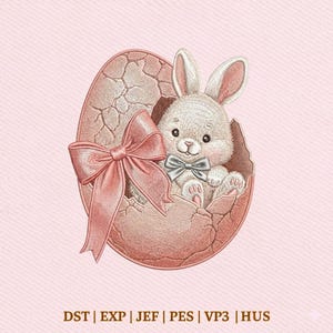 Peut inclure: Broderie d'un lapin blanc sortant d'un œuf rose fissuré, orné d'un nœud rose et d'un nœud papillon argenté. Le motif est posé sur un fond rose. Le texte en bas indique : DST | EXP | JEF | PES | VP3 | HUS.
