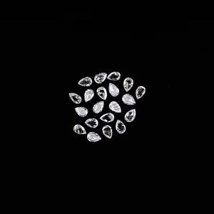 May include: A collection of twenty-two small, clear, pear-shaped faceted gemstones arranged in a loose cluster against a solid black background. Each individual stone features multiple facets that reflect light, creating a bright, sparkling appearance.