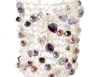 May include: A silver wire crocheted bracelet with a variety of colorful beads and stones, including purple, pink, green, and brown.