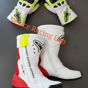 May include: White and black motorcycle boots and gloves. The boots have red and yellow accents, with a zipper closure. The gloves are white with black, red, and yellow details. The gloves and boots have a star logo.
