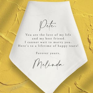 May include: White handkerchief with a handwritten message that reads "Pete. You are the love of my life and my best friend. I cannot wait to marry you. Here's to a lifetime of happy tears! Forever yours, Melinda."