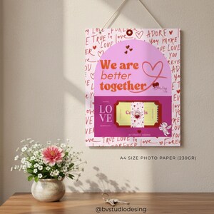 Puede incluir: Una impresión decorativa con las palabras "We are better together" en rosa y rojo. La impresión presenta un diseño de boleto y está decorada con corazones y las palabras "Love" y "Forever". La impresión está colgada en una pared.