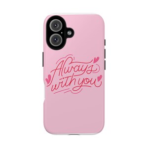 Puede incluir: Funda de teléfono rosa con la frase "Always with you" en cursiva roja, adornada con corazones. Borde blanco y apertura para la cámara. Un accesorio elegante.
