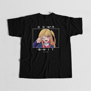 May include: A black short-sleeve t-shirt featuring a graphic of an anime character with blonde hair making a peace sign. The text "D O N'T" appears above the graphic and "Q U I T" below it, with "ELF APPAREL" printed in smaller text at the bottom.