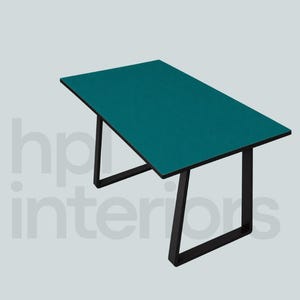 Op de afbeelding: Een rechthoekige tafel met een effen blauwgroen tafelblad en een zwart metalen frame. Het onderstel bestaat uit twee trapeziumvormige poten die verbonden zijn door een horizontale steunbalk. De tekst hp interiors is zichtbaar op de achtergrond.