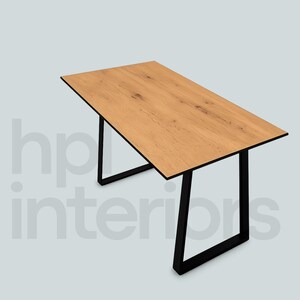 Könnte beinhalten: Ein rechteckiger Esstisch mit einer hellbraunen Holzmaserung und sichtbarer natürlicher Textur. Der Tisch wird von zwei schwarzen, U-förmigen Metallbeinen an beiden Enden getragen. Der Text hp interiors ist im Hintergrund zu sehen.