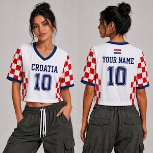 May include: A white cropped jersey with a V-neck, featuring red and white checkered side panels and sleeves. The front displays the text CROATIA and the number 10 in blue. The back shows the text YOUR NAME, the number 10, and a small Croatian flag.