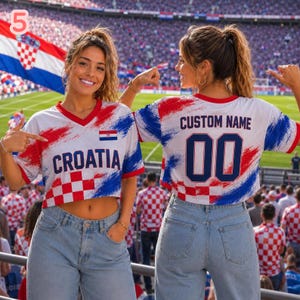 May include: A white V-neck crop top featuring red and blue brushstroke patterns, the text CROATIA, a small Croatian flag, and the back displaying CUSTOM NAME with the number 00 in dark blue, paired with light blue denim jeans.
