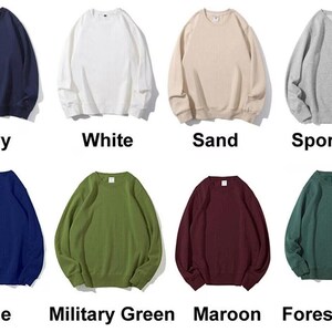 May include: A collection of crewneck sweatshirts in various colors, including black, navy, white, sand, sport grey, light pink, red, blue, military green, maroon, and forest green. Each sweatshirt is displayed with its color name.