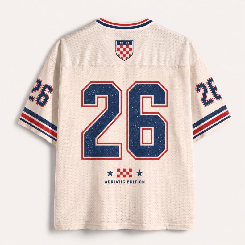 Pu&ograve; includere: Una maglia in mesh color bianco sporco con il numero 26 in grandi cifre blu con bordi rossi sul retro. Il design include uno stemma a scacchi rosso e bianco, strisce blu e rosse sulle maniche e la scritta ADRIATIC EDITION con due stelle.