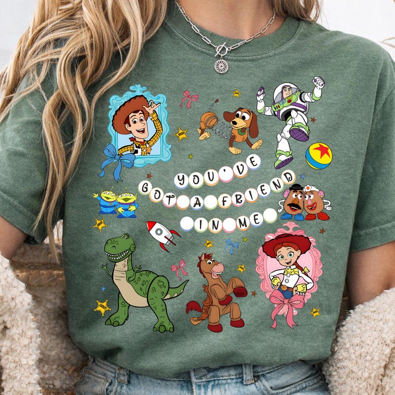 May include: Green t-shirt featuring colorful cartoon characters and the phrase "You've Got a Friend in Me." The design includes images of Woody, Buzz Lightyear, and other characters from the animated movie.