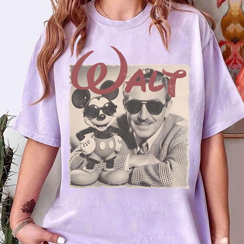 Puede incluir: Camiseta de color lila claro con un gr&aacute;fico vintage de Mickey Mouse y Walt Disney con gafas de sol. La palabra "Walt" est&aacute; impresa en rojo, con una fuente estilizada sobre la imagen. La camiseta tiene mangas cortas.