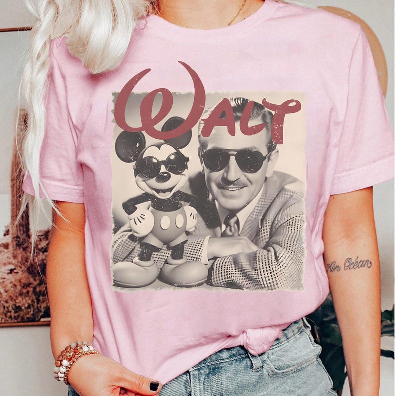 Puede incluir: Camiseta rosa claro con un gr&aacute;fico retro de Mickey Mouse con gafas de sol y un retrato de Walt Disney. La palabra "Walt" est&aacute; escrita encima de la imagen en una fuente estilizada. La camiseta tiene mangas cortas.