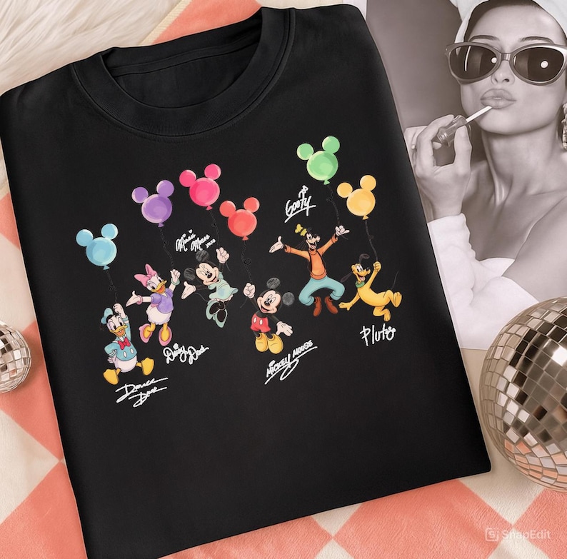 May include: Black crew neck sweatshirt with a colourful graphic of Disney characters holding balloons. The characters include Donald Duck, Daisy Duck, Minnie Mouse, Mickey Mouse, Goofy, and Pluto. Each character has their name written below them.