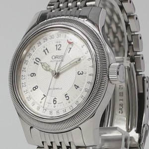 May include: Silver wristwatch with a white dial, black numerals, and a date display. The watch has a textured dial, a fluted bezel, and a stainless steel strap. The watch face displays the brand name "ORIS" and "25 JEWELS".