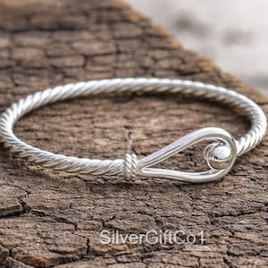 May include: A white ceramic mug with a black handle and the text "But First, Coffee" in a bold, black font. The mug is set against a blurred background, suggesting a cozy setting.