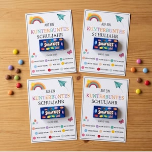 Puede incluir: Cuatro tarjetas rectangulares blancas con el texto AUF EIN KUNTERBUNTES SCHULJAHR y GANZ VIEL, con ilustraciones de un arcoíris, un avión de papel y una mariposa. Cada tarjeta tiene una caja azul de Smarties mini y caramelos de colores.