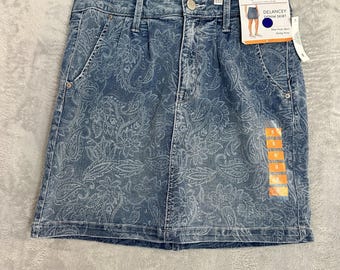 Peut inclure: Une jupe en jean bleu avec un imprimé cachemire blanc, une fermeture à bouton et éclair, et cinq poches. La jupe porte une étiquette Seven7 Delancey Denim Skirt et un autocollant de taille 8. Elle est suspendue à un cintre en métal.
