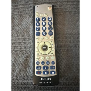 May include: A silver and black Philips Universal remote control with numerous buttons. The remote has a power button, number pad, volume controls, and channel controls. The Philips logo is at the bottom.