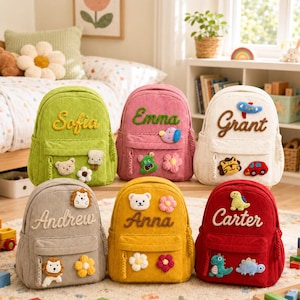 Puede incluir: Seis mochilas de pana en verde lima, rosa, crema, gris, amarillo y rojo. Cada mochila presenta un nombre bordado en cursiva y varias aplicaciones de felpa que incluyen flores, animales, un coche y un avión en el bolsillo delantero.
