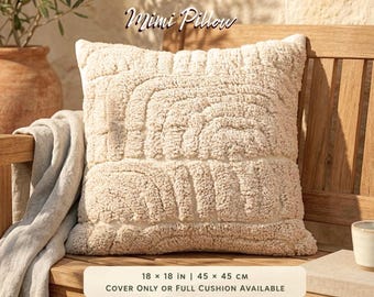 Puede incluir: Un cojín cuadrado Mimi Pillow con textura de mechones color crema y patrones de arco en relieve. El cojín mide 45 x 45 cm. El texto Mimi Pillow es visible sobre el cojín, y el texto 18 x 18 in | 45 x 45 cm aparece debajo.