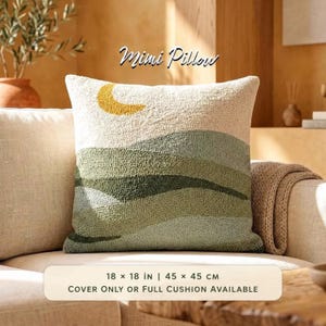 May include: A square Mimi Pillow featuring a textured, tufted landscape design with rolling green hills and a yellow crescent moon against an off-white background. The pillow measures 45 x 45 cm and is available as a cover or full cushion.