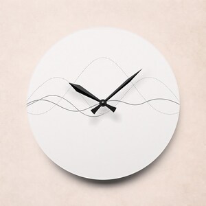 May include: A minimalist white wall clock with black hands and a subtle wave design. The clock face features a clean, uncluttered aesthetic, with a simple, modern design. The hands are black and the clock is round.