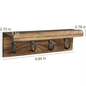 May include: A rustic wooden key holder with four metal hooks. The shelf is 9.84 inches long, 3.1 inches wide, and 2.75 inches high. The key rack is made of dark brown wood and has a small shelf above the hooks.