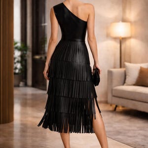 Back view of black one shoulder leather dress with layered fringe midi skirt, asymmetrical design evening outfit shown in luxury indoor setting