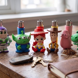 May include: A collection of six plastic lighter cases featuring Toy Story character figures including Buzz Lightyear, an alien, Jessie, Woody, Hamm, and Rex. Each figure is attached to a standard metal lighter mechanism in various colors.