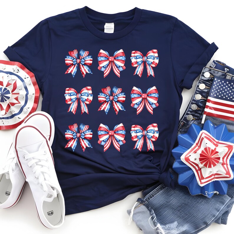 May include: Navy blue t-shirt featuring nine bows with a patriotic red, white, and blue design. The bows have a star and stripe pattern. The image also includes white sneakers, denim jeans, and decorative patriotic items.