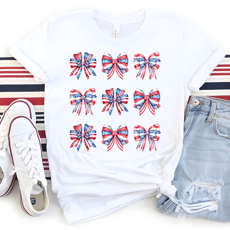 May include: White t-shirt featuring nine watercolor bows in red, white, and blue, with a patriotic stars and stripes design. The shirt is styled with white sneakers and blue jeans, perfect for a casual, festive look.