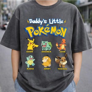 May include: A white ceramic mug with a black handle and the text "But First, Coffee" in a bold, black font. The mug is set against a blurred background, suggesting a cozy setting.