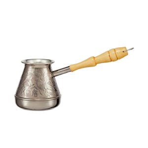 May include: A metallic coffee pot with a wide base and a narrow neck, featuring an embossed bird and floral pattern on the exterior. The pot has a long, light-coloured wooden handle with a small metal loop at the end for hanging storage.