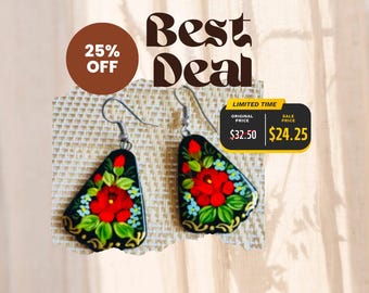 May include: A pair of black drop earrings featuring a hand-painted floral design with vibrant red roses, green leaves, and small blue flowers. The earrings have silver-toned metal hooks and a smooth, glossy finish on the teardrop-shaped surfaces.