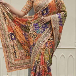 May include: A vibrant, patterned saree in shades of orange, purple, and green. The fabric features intricate designs and is embellished with shimmering details along the borders. The saree's design includes a matching blouse with similar patterns.