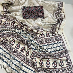 May include: Cream-coloured fabric with a detailed pattern. The design includes a mix of floral and geometric elements in navy blue and burgundy. A matching patterned piece sits atop the fabric, completing the ensemble.