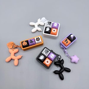 Peut inclure: Un ensemble de quatre jeux de touches pour clavier mécanique sur le thème d'Halloween, avec des cadres orange, blancs, violets et noirs. Chaque jeu présente des icônes de fantômes, crânes, citrouilles et toiles d'araignée, avec des porte-clés en forme d'animaux en ballon.