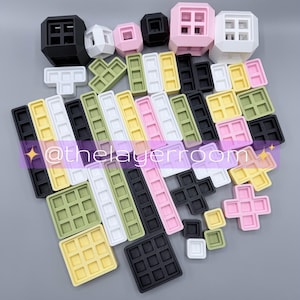 Peut inclure: Un ensemble de blocs de construction g&eacute;om&eacute;triques color&eacute;s de diff&eacute;rentes formes et tailles. Les blocs sont dans des tons de noir, blanc, rose, jaune et vert. Certains blocs ont une texture gaufr&eacute;e, tandis que d'autres sont en forme de cube.
